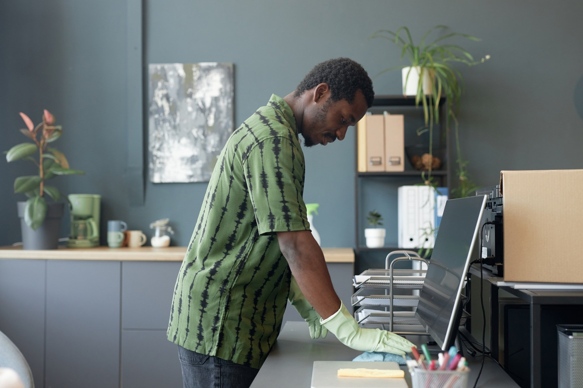 Black Man Cleaning Desk at Office in Rubber Gloves