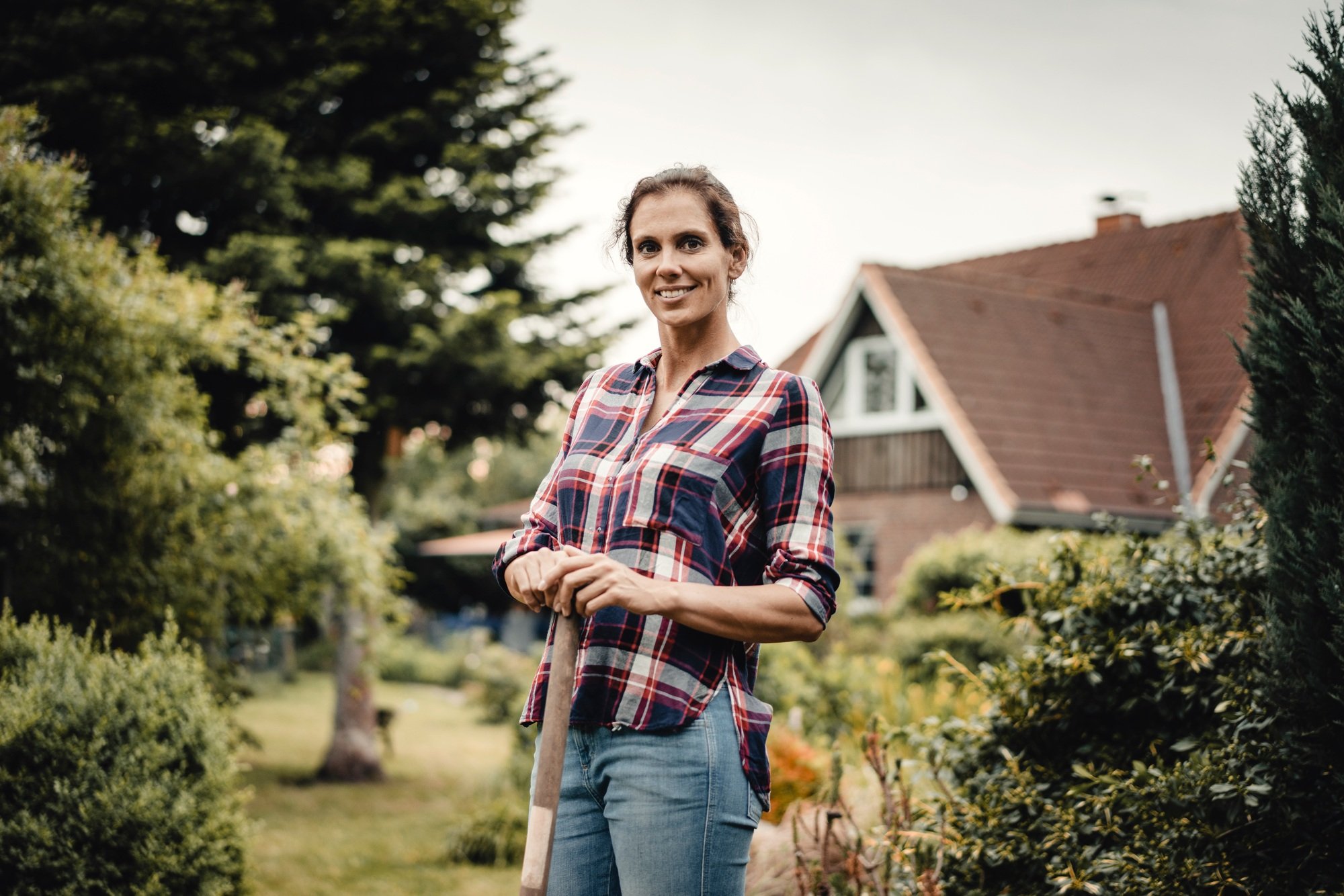 Proud home owner standing in her garden with a spade