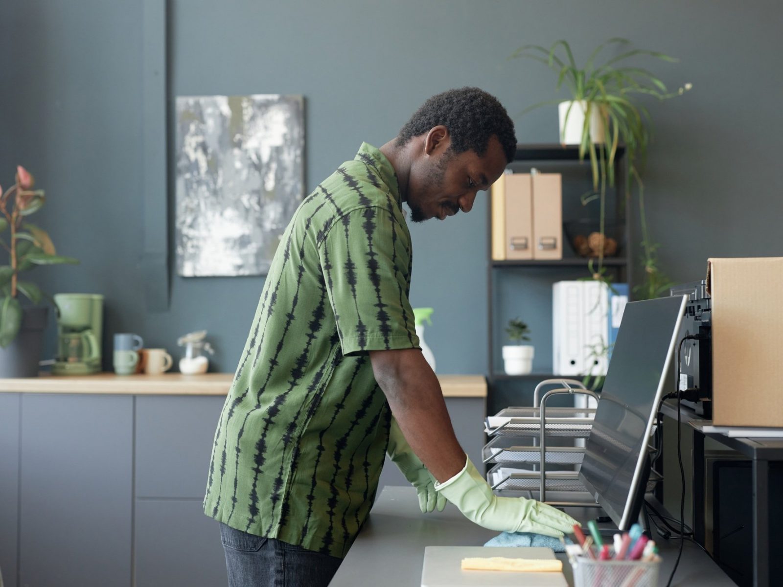 Black Man Cleaning Desk at Office in Rubber Gloves