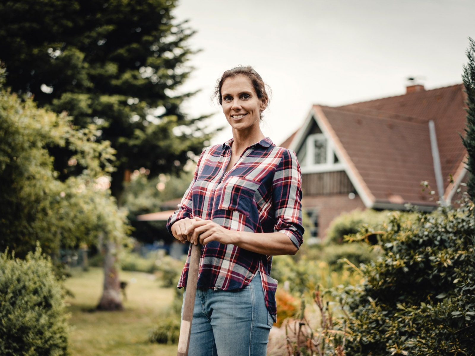 Proud home owner standing in her garden with a spade
